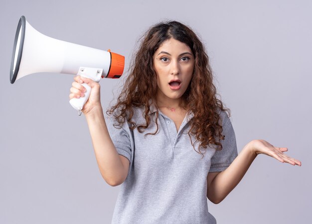 Impressed young pretty caucasian girl  holding speaker showing empty hand isolated on white wall