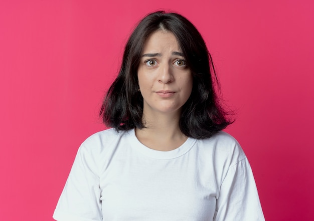 Impressionato giovane ragazza piuttosto caucasica guardando la telecamera isolata su sfondo cremisi