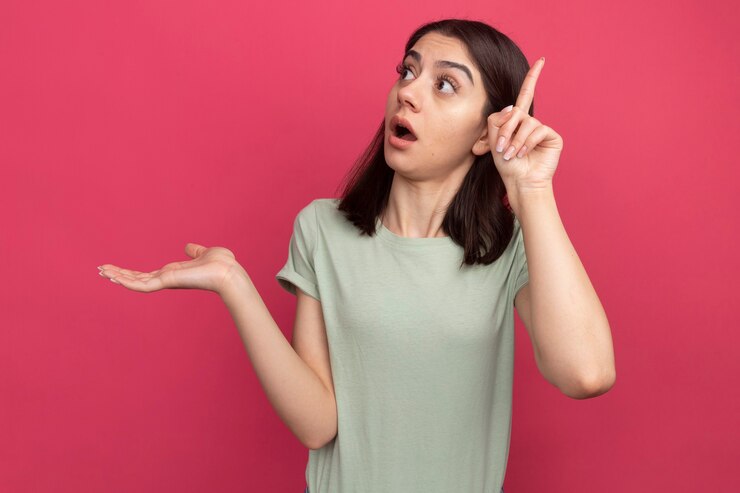 Free Photo impressed young pretty caucasian girl showing empty hand looking at side pointing up isolated on pink wall