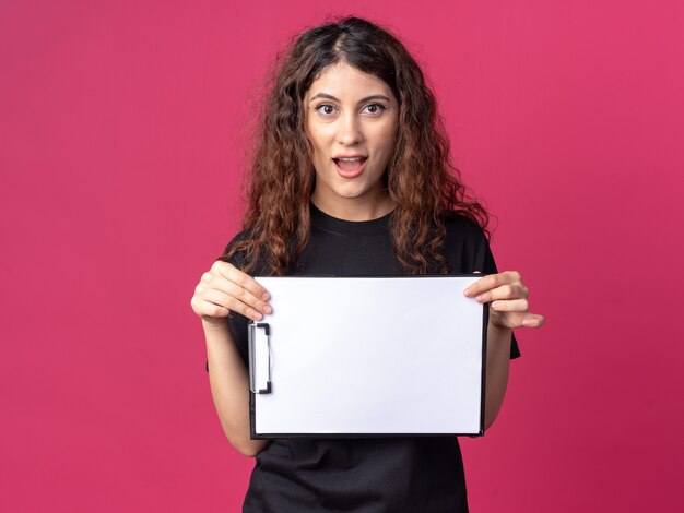 Impressed young pretty girl holding clipboard 