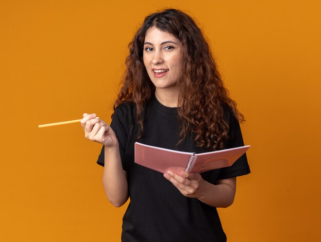 Impressed young pretty girl holding pencil and note pad 