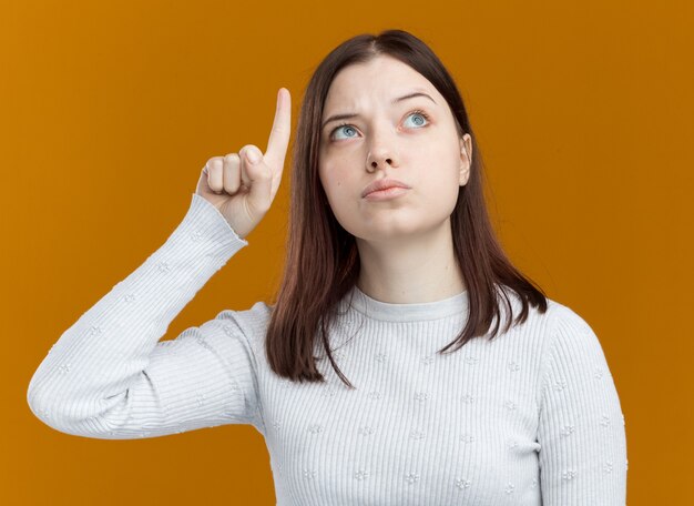 Foto gratuita giovane bella ragazza impressionata che guarda e indica verso l'alto