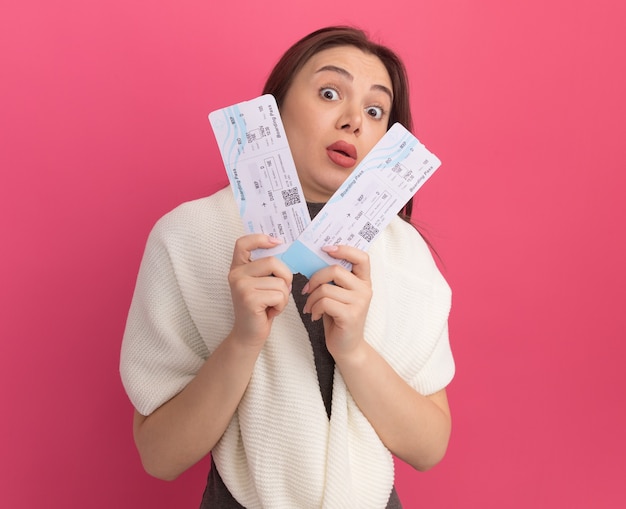 Impressed young pretty woman holding airplane tickets 