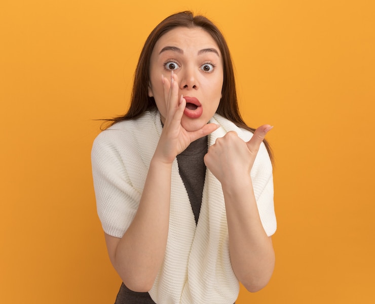 無料Photo 横を向いて口の近くに手を保つ感動の若いきれいな女性