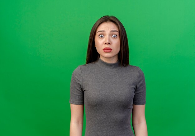 Impressed young pretty woman looking at camera isolated on green background with copy space