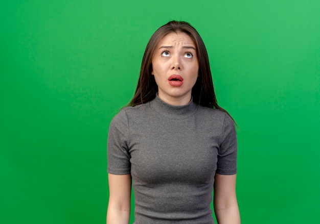 Free photo impressed young pretty woman looking up isolated on green background with copy space