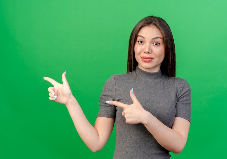 Free Photo impressed young pretty woman pointing at side isolated on green background