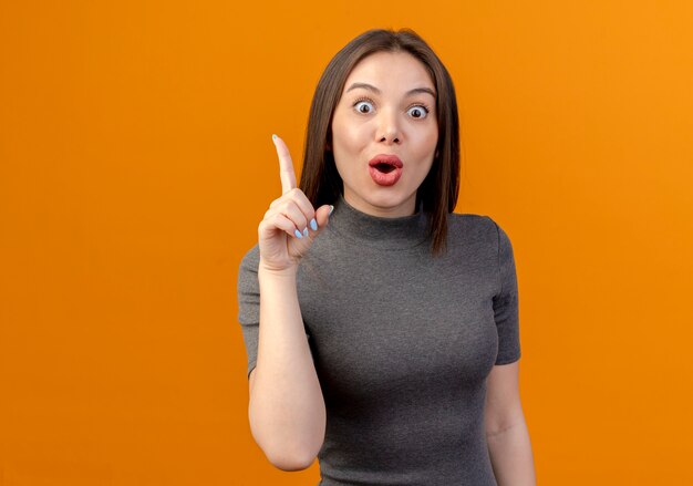Impressed young pretty woman raising finger isolated on orange background with copy space