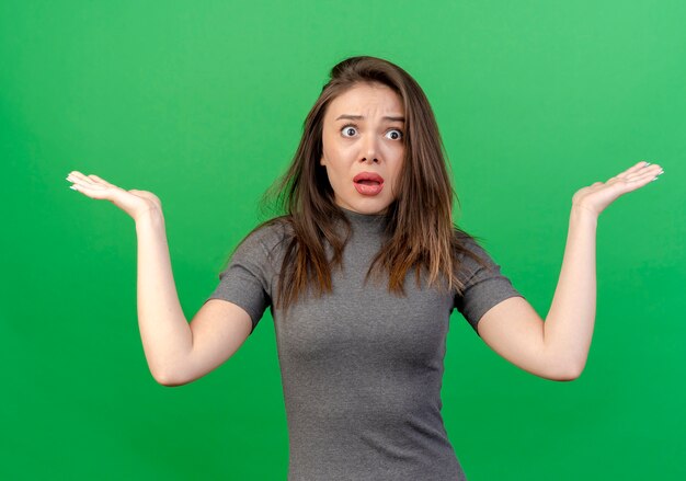 Impressed young pretty woman showing empty hands isolated on green background