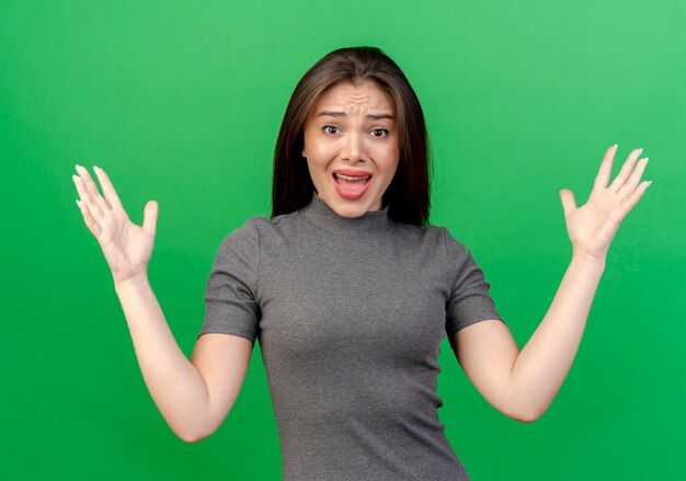 Impressed young pretty woman showing empty hands isolated on green background