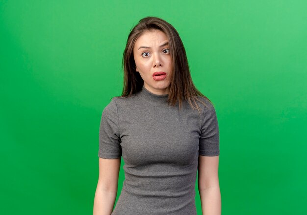 Impressed young pretty woman standing with crossed eyes isolated on green background with copy space