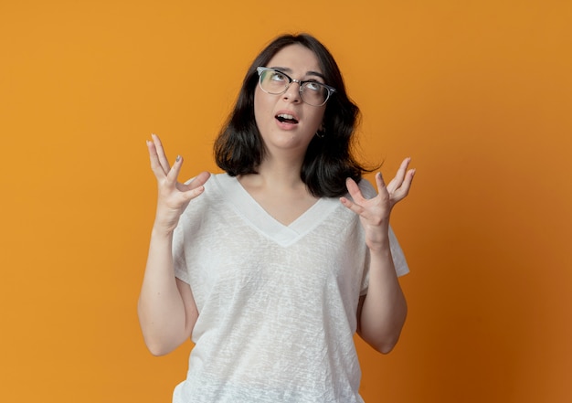 Free photo impressed young pretty woman wearing glasses looking up and keeping hands in air