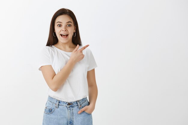 Impressed young woman posing against white wall