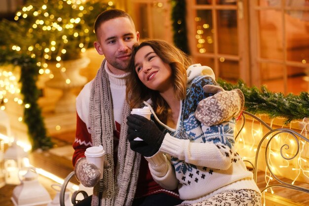 Inbetween Christmas decorations romantic couple enjoying hot drinks while have a date.