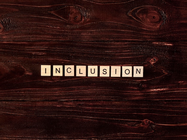 Free photo inclusion word written in scrabble letters on wooden background