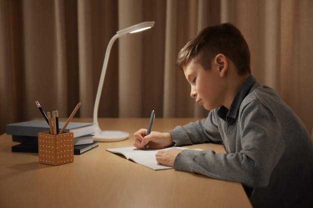 Incorrect posture concept. schoolboy sitting at table in room