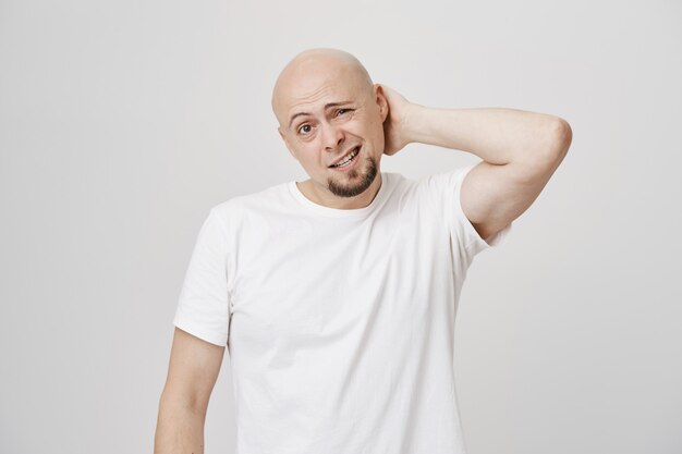 Indecisive bald guy scratching back, look puzzled