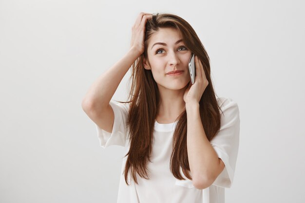 Indecisive cute girl make decision during phone call, look hesitant