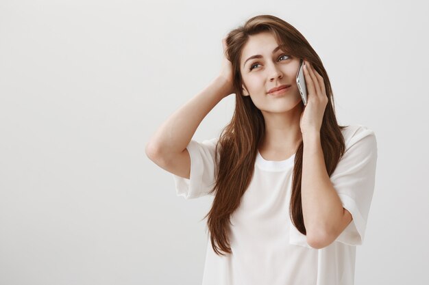 Indecisive cute girl make decision during phone call, look hesitant