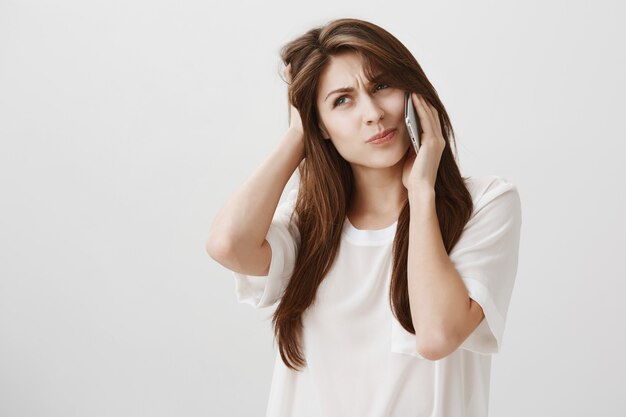 Indecisive cute girl make decision during phone call, thinking and looking left unsure