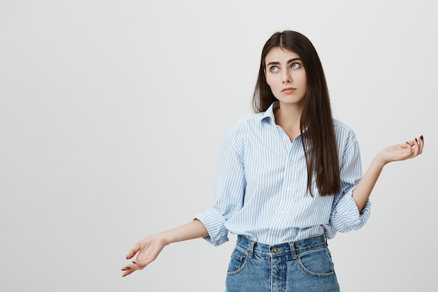 Indecisive cute woman shrugging, hesitating over choice