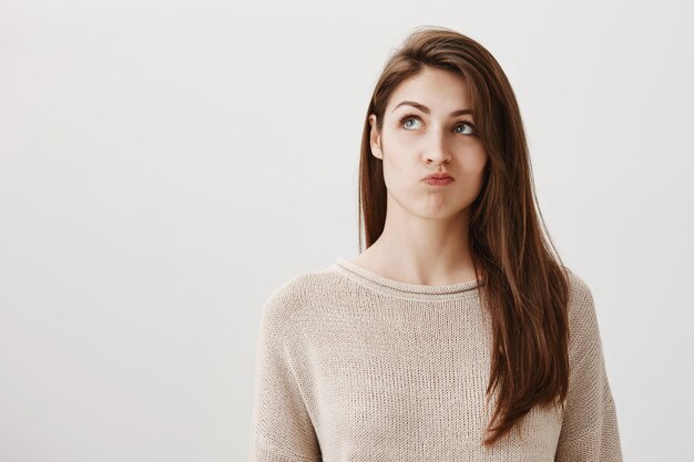 Indecisive thoughtful girl making decision, looking upper left corner hesitant