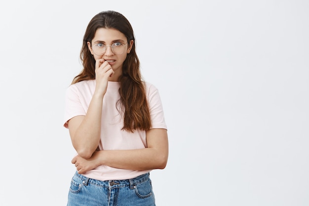 Indecisive young brunette with glasses posing