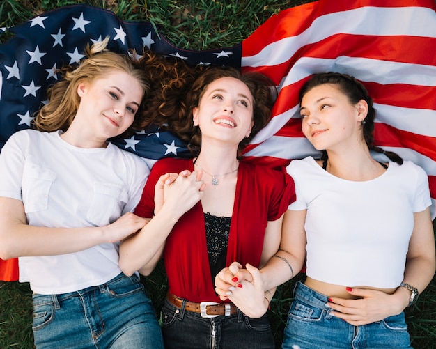 Concetto di festa dell'indipendenza con ragazze che si trovano sulla bandiera americana