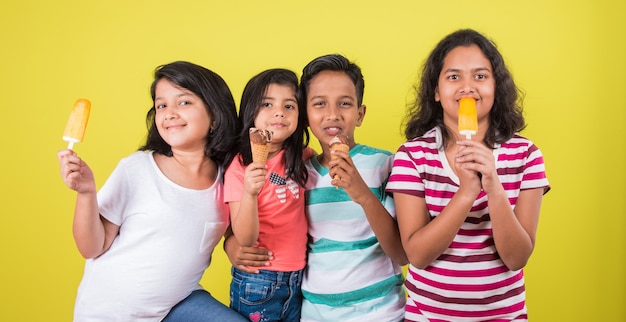 Indian or asian cute little kids eating ice cream or mango bar or candy. isolated over colourful background