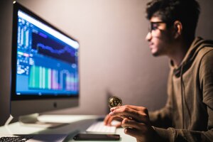 Indian bitcoin trader checking stock trading data analysis concept working in office with financial graph on computer monitors