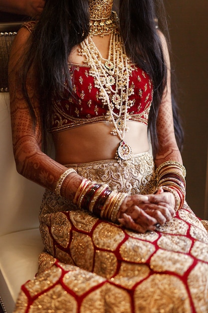 Бесплатное фото Индийская невеста в великолепном красном костюме сидит на белом стуле