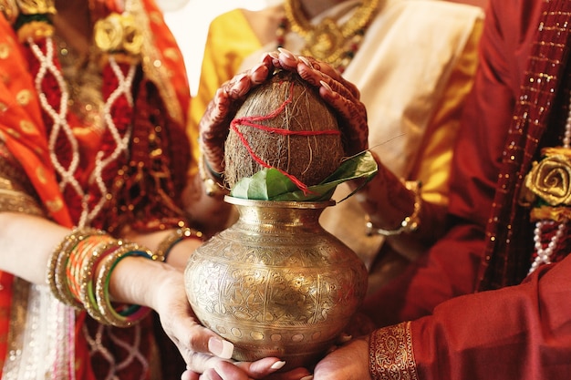 インドの花嫁の両親は、彼女の手の下にココナッツとボウルを保持