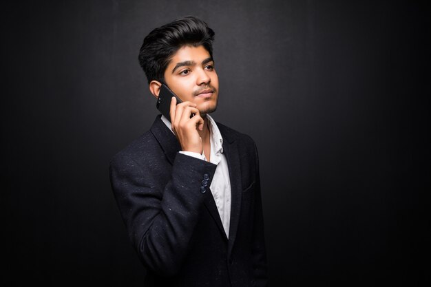 Indian business man talking on phone on black wall