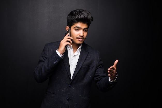 Indian business man talking on phone on black wall