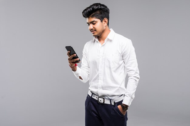 白い壁とスマートフォンを使用してインドのビジネスの男性