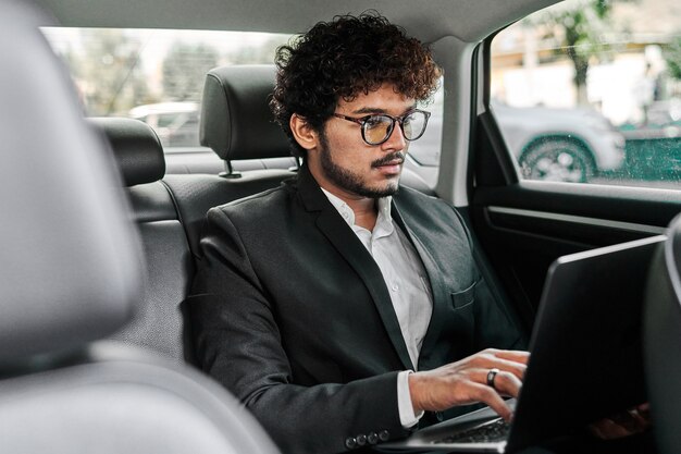 Indian businessman in the backseat working.