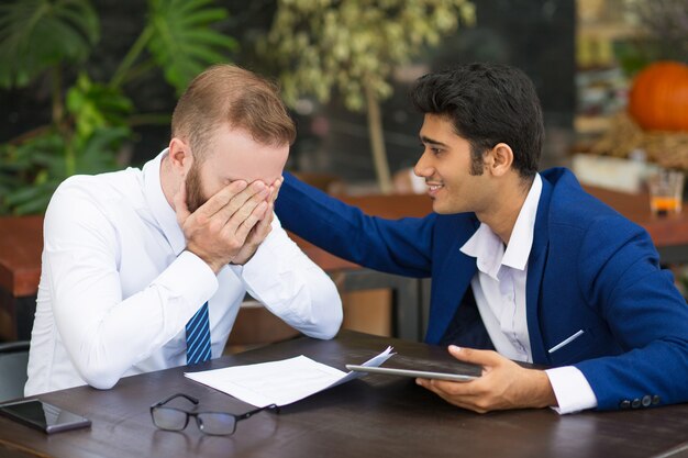 Indian businessman supporting colleague and stroking his back