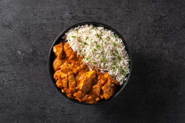 Indian butter chicken in black bowl on black background