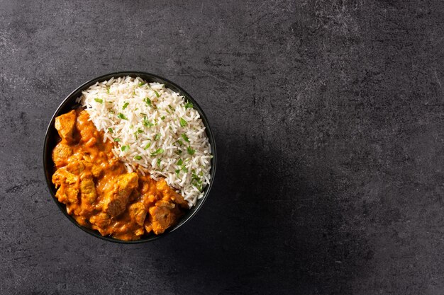 Indian butter chicken in black bowl on black background