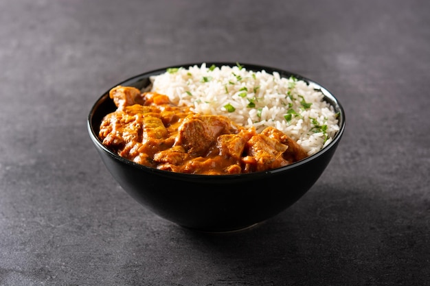 Free photo indian butter chicken in black bowl on black background