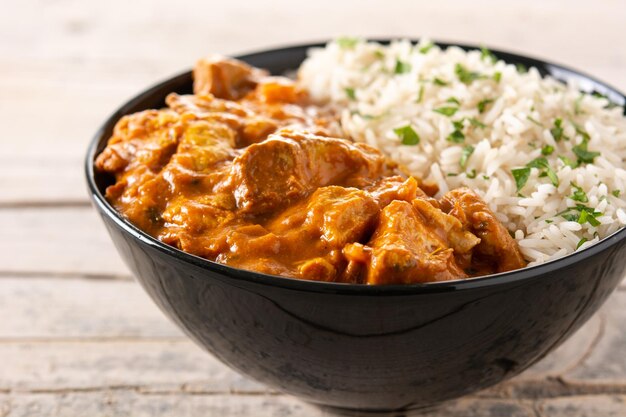 Indian butter chicken in black bowl on wooden table