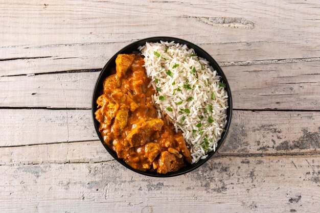 Indian butter chicken in black bowl on wooden table