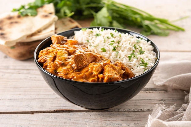 Indian butter chicken in black bowl on wooden table