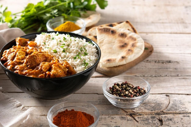 Indian butter chicken in black bowl on wooden table