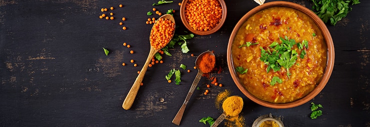 Free Photo indian dhal spicy curry in bowl, spices, herbs, rustic black wooden table.