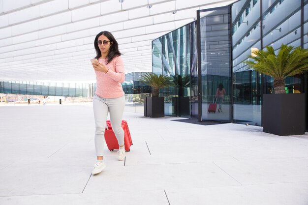 Indian girl carrying wheeled luggage and running to airport