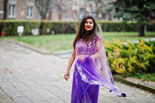 Индийская индуистская девушка в традиционном фиолетовом сари позирует на осенней улице