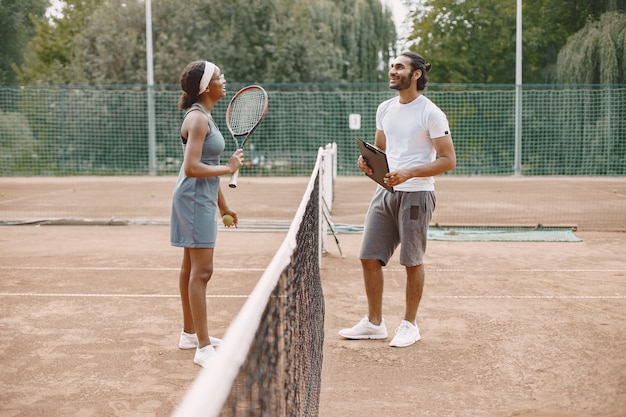 Indian man and black american woman standing on a tennis court