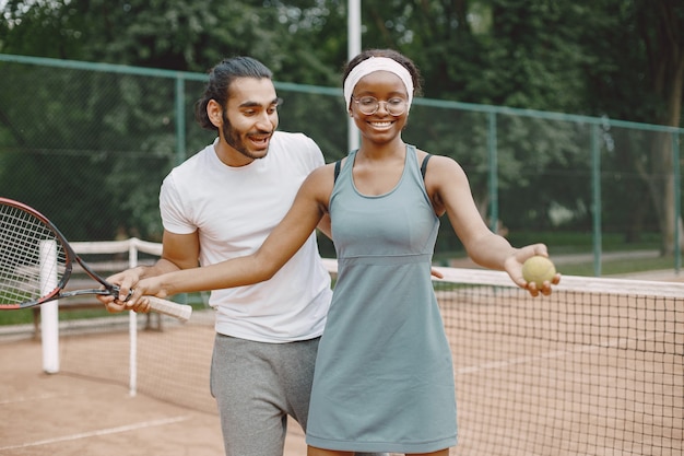 테니스 코트에 서 있는 인도 남자와 흑인 미국 여자