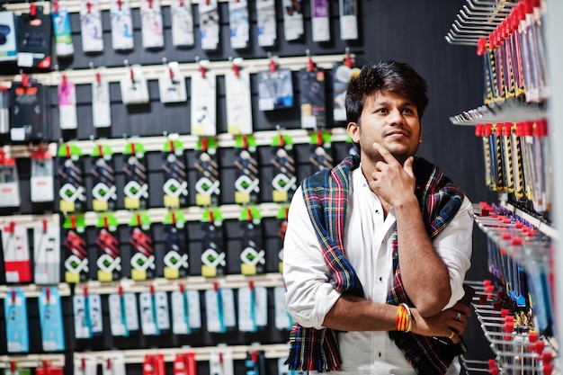 携帯電話店でインド人の顧客のバイヤーは彼のスマートフォンのケースを選択します南アジアの人々と技術の概念携帯電話ショップ
